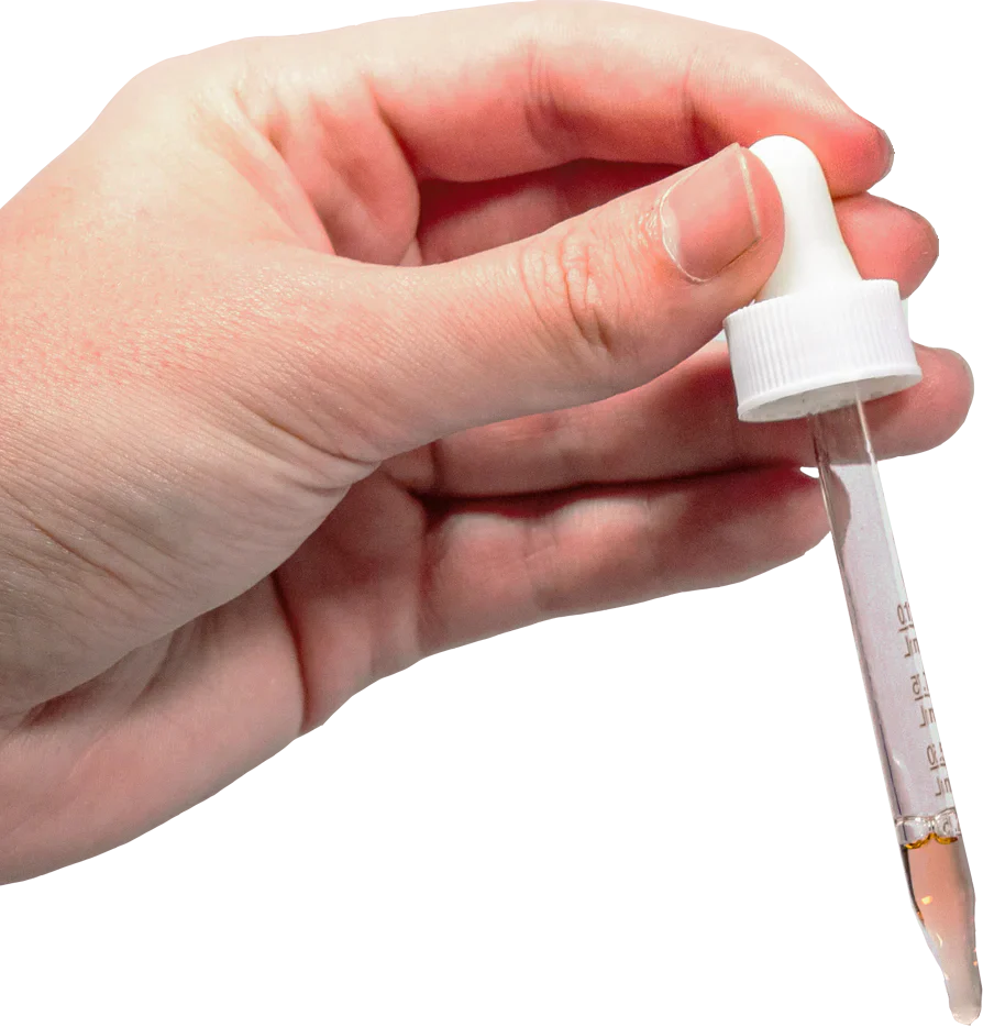 Hand holding a white dropper pipette with amber liquid in the tip and measurement markings.