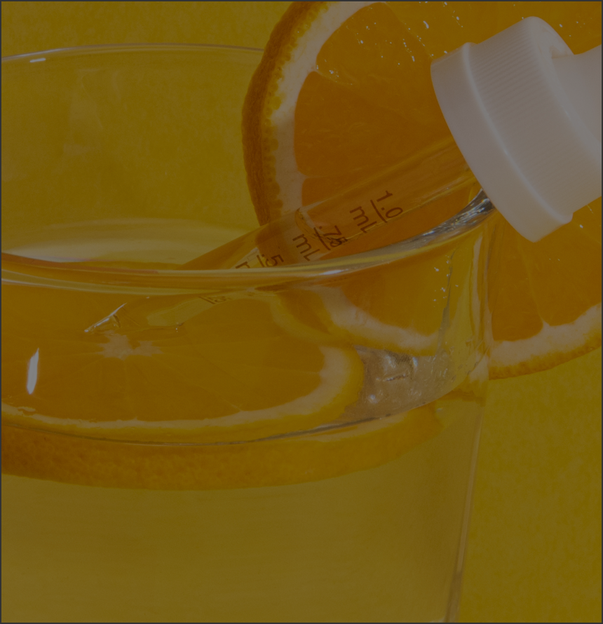 Dropper resting in a glass of water with orange slices, dropper markings visible: 1.0 mL, 0.75 mL, 0.5 mL