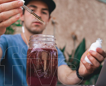 Man adding drops from a dropper into a Ball mason jar of purple smoothie; translucent 'five' overlay with 'TM'.